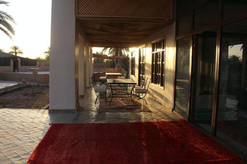 a patio with a table and a red rug at Bab Rimal - Desert Hotel in M'hamid El Ghizlane in Mhamid