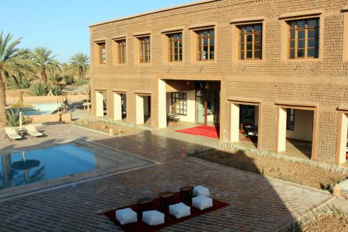 a building with a swimming pool in front of it at Bab Rimal - Desert Hotel in M'hamid El Ghizlane in Mhamid
