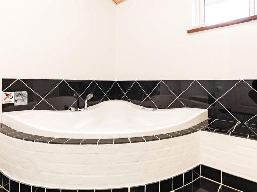 y baño con bañera y azulejos negros. en 6 person holiday home in L kken, en Løkken