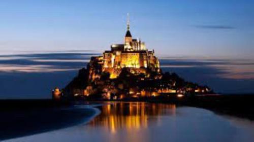 un château sur une île dans l'eau la nuit dans l'établissement Maison au pied du Mont Saint Michel 2, à Pontorson