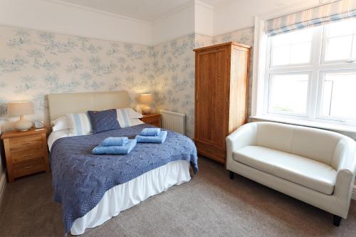 a bedroom with a bed and a chair and a window at Camberley House in Sheringham