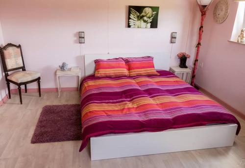 ein Schlafzimmer mit einem großen Bett mit einer bunten Decke in der Unterkunft La maison d'Huguette in Profondeville