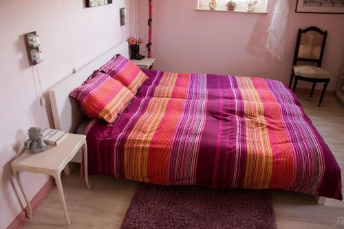 sypialnia z dużym łóżkiem i kolorowym kocem w obiekcie La maison d'Huguette w mieście Profondeville