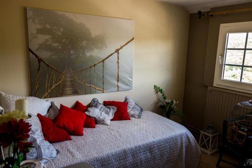 - une chambre dotée d'un lit avec des oreillers rouges et un tableau dans l'établissement La maison d'Huguette, à Profondeville