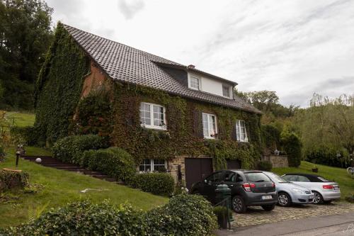 een huis met auto's die ervoor geparkeerd staan bij La maison d'Huguette in Profondeville