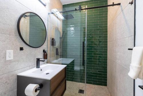 a bathroom with a sink and a shower with green tiles at Thena Hotel- Lux Studio in Philadelphia