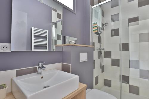 Brit Hotel Marbella في بياريتز: حمام مع حوض أبيض ومرآة