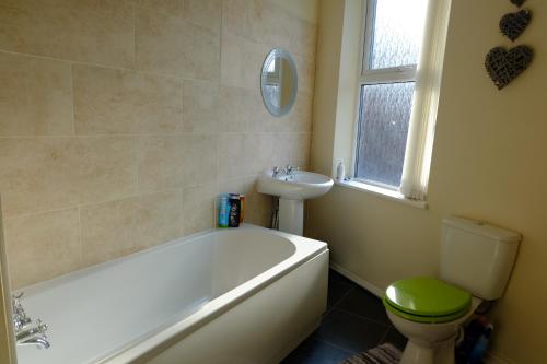 a bathroom with a tub and a toilet and a sink at Lovely Master Bedroom with King Size Bed in Liverpool