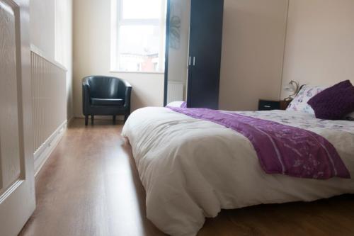 um quarto com uma cama e uma cadeira preta em Lovely Master Bedroom with King Size Bed em Liverpool