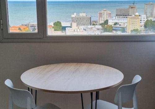 a table and chairs in front of a window at Infinito - Departamento con vista al mar in Comodoro Rivadavia