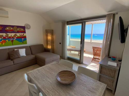 Sala de estar con mesa y sofá y el océano en Corallo Beachfront Penthouse by Bobbywashere, en Santa Maria