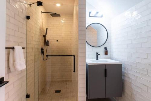 a bathroom with a shower and a sink and a mirror at Thena Hotel - Spacious Studio in Philadelphia