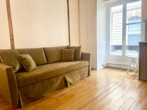 un divano marrone in soggiorno con pavimento in legno di Electra mini-studio a Parigi