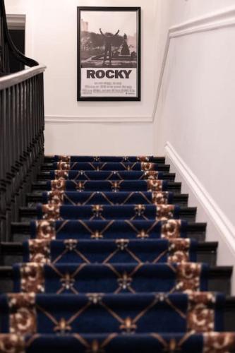 a staircase with a blue carpet and a picture on the wall at Thena Hotel - Beautiful 1 Bedroom in Philadelphia