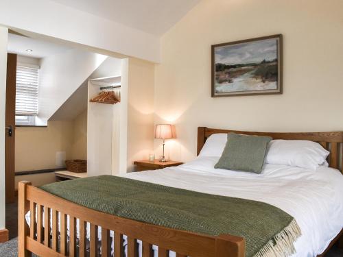 a bedroom with a large bed with a green blanket at Y Parlwr in Kidwelly