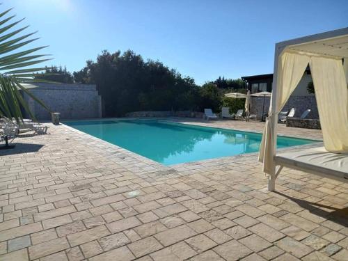 a large swimming pool with a canopy and a patio at La Carcara in Otranto