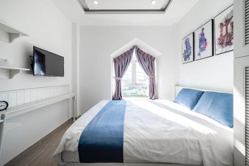 a white bedroom with a bed and a window at Cozrum Homes - Sonata Residence in Ho Chi Minh City