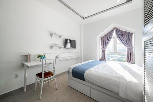 a bedroom with a bed and a desk and a window at Cozrum Homes - Sonata Residence in Ho Chi Minh City