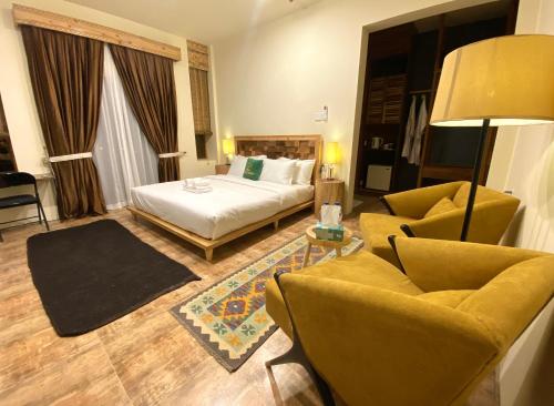 Dumani Nagar Hotel & Resort في هنزه: غرفه فندقيه بسرير واريكه وكراسي