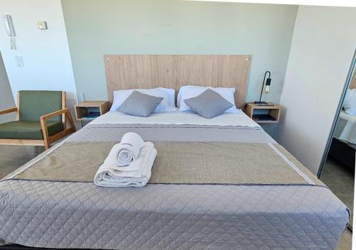 1 dormitorio con 1 cama grande y toallas. en Infinito - Departamento con vista al mar en Comodoro Rivadavia