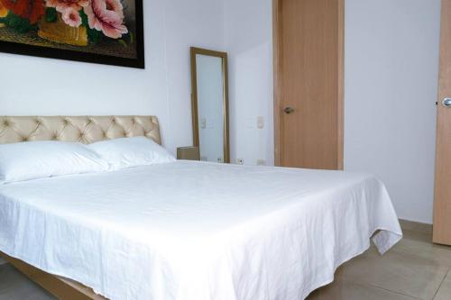 1 dormitorio con 1 cama blanca con manta blanca en Apartamento viajes de trabajo en el norte en Montería