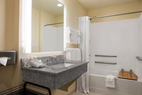 y baño con lavabo de granito y ducha. en Days Inn & Suites by Wyndham Caldwell en Caldwell