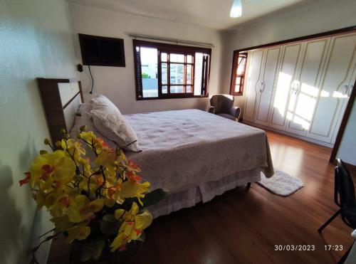 a bedroom with a bed and a vase of flowers at Pousada com vista para o Cristo 3 in Encantado