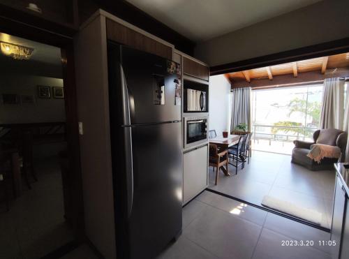 a kitchen with a stainless steel refrigerator and a living room at Pousada com vista para o Cristo 3 in Encantado