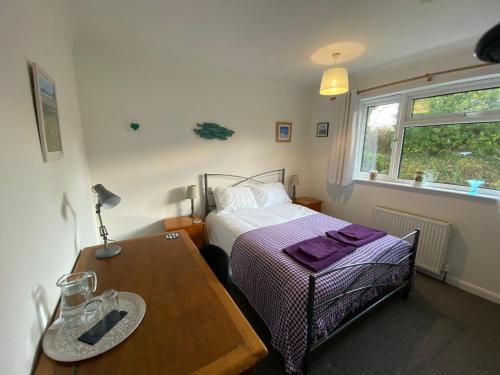 Dormitorio pequeño con cama y mesa en Agapanthus Bed & Breakfast - Fraddam en Hayle