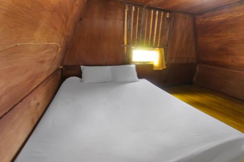 a small bedroom with a white bed in a boat at SPOT ON 92462 Awenk Homestay in Lombok