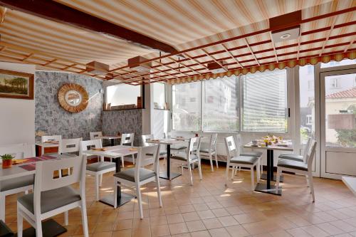 a restaurant with white chairs and tables and windows at Hotel Marbella in Biarritz