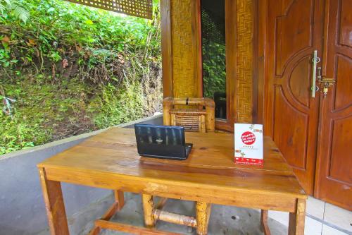 a wooden table with a laptop sitting on top of it at SPOT ON 92462 Awenk Homestay in Lombok