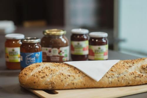 Una hogaza de pan en una tabla de cortar con frascos de mermelada en easyHotel Paris Nord Aubervilliers, en Aubervilliers