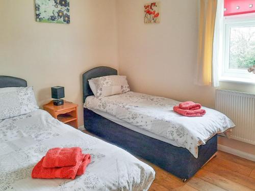 Goxhill的住宿－Cowslip Cottage- W43122，卧室内的两张床,上面有红色毛巾