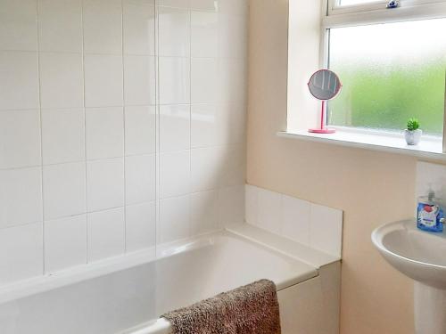 a bathroom with a bath tub and a sink at Cowslip Cottage- W43122 in Goxhill
