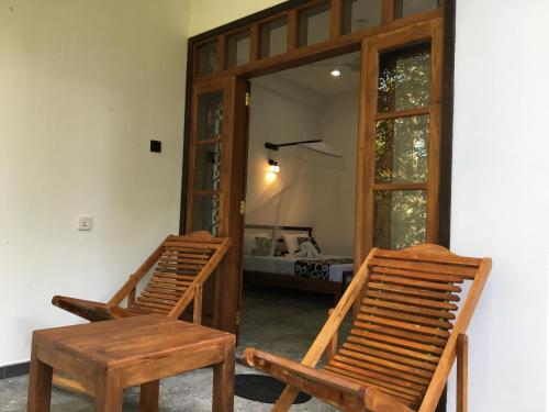 2 sedie in legno e un tavolo in una stanza di Peacock Riverside Eco Lodge a Udawalawe