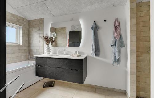 a bathroom with a sink and a tub and a mirror at Beautiful Home In Nyborg With Wifi And 3 Bedrooms in Nyborg