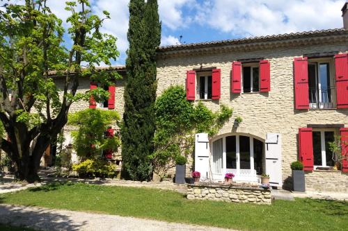 une maison avec des volets rouges et un arbre dans l'établissement Le Mas de Jalique - Isle-sur-la-Sorgue, à LʼIsle-sur-la-Sorgue