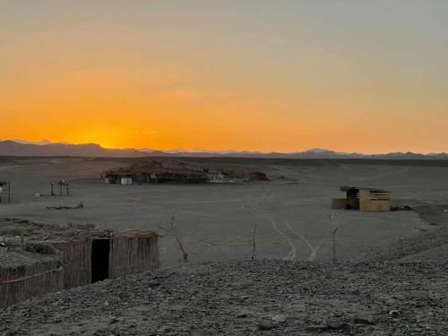 una vista de un desierto con una puesta de sol en el fondo en Apadi camp en Coraya Bay