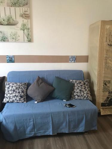 a blue couch in a living room with pillows at Joli T1 classe 2* avec balcon proche plages in Saint-Gilles les Bains