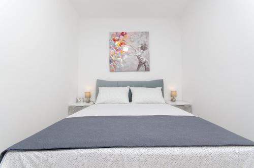 a white bedroom with a large bed and a painting at Blue moon Split Apartment in Split