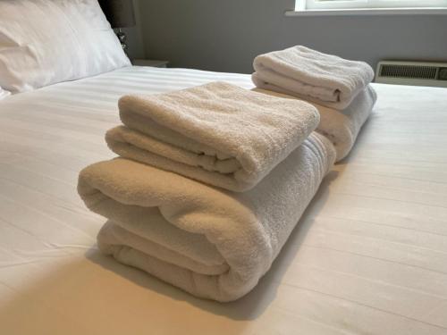 three towels are stacked on top of a bed at Luxury Riverside City Centre Apartment in York