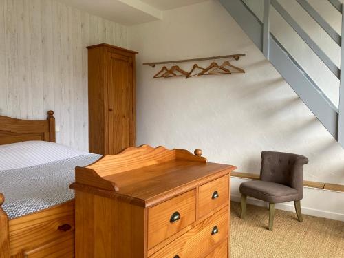 ein Schlafzimmer mit einem Bett, einer Holzkommode und einem Stuhl in der Unterkunft Gîte La Maison de JuJu in Lacave