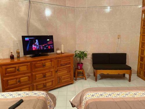 uma sala de estar com televisão numa cómoda de madeira em Habitación independiente a unos pasos del centro em Taxco de Alarcón
