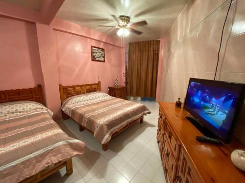 um quarto com 2 camas e uma televisão de ecrã plano em Habitación independiente a unos pasos del centro em Taxco de Alarcón