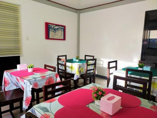 uma sala de jantar com duas mesas e cadeiras com tapetes cor-de-rosa em E & C Hotel em Laoag