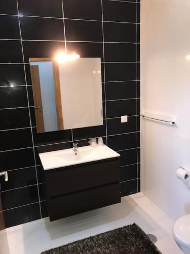 a black tiled bathroom with a sink and a mirror at Restaurante Residencial Pizzaria S. Estevão in Aguiar da Beira