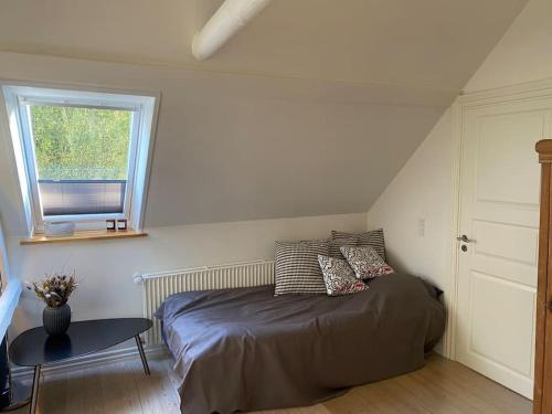 a bedroom with a bed and a table and a window at Naturskøn landidyl på Ibækgaarden - I egen bolig in Vejle