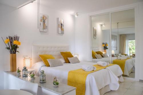 ein weißes Schlafzimmer mit einem großen Bett und gelben Kissen in der Unterkunft Miraflores, beach apartment, apartamento en la playa ! in Mijas Costa