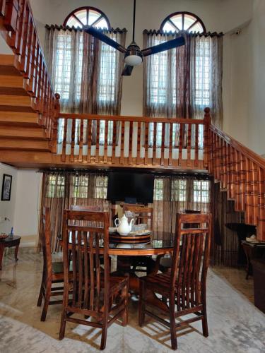a dining room with a wooden table and a staircase at The Nook Home in Ernakulam